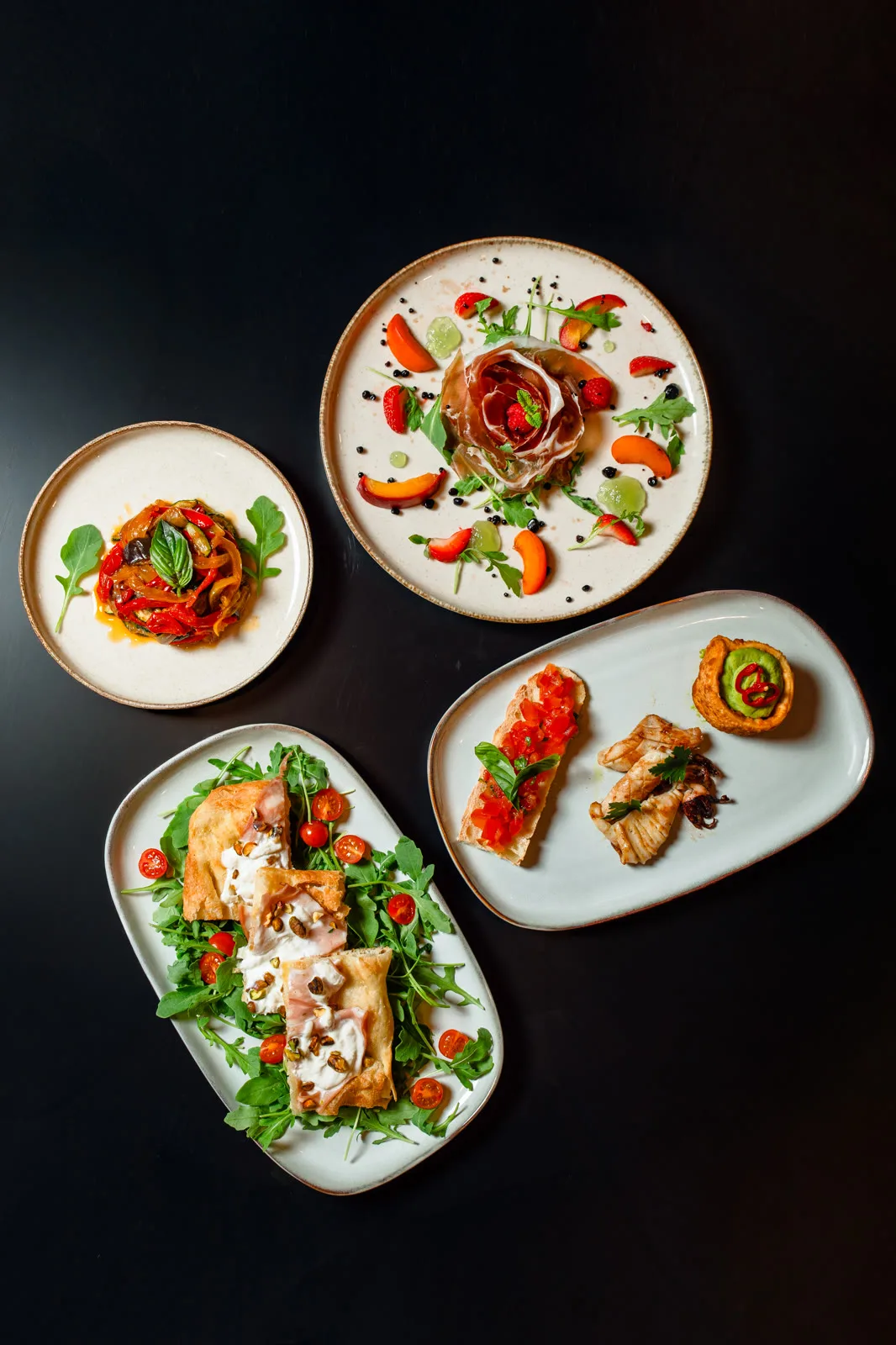 Quatre assiettes dressées vues du dessus — restaurant La Nonna